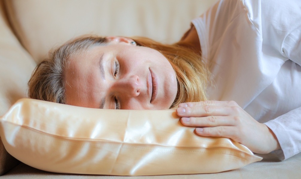 Close-up of a woman's face resting on a satin pillowcase