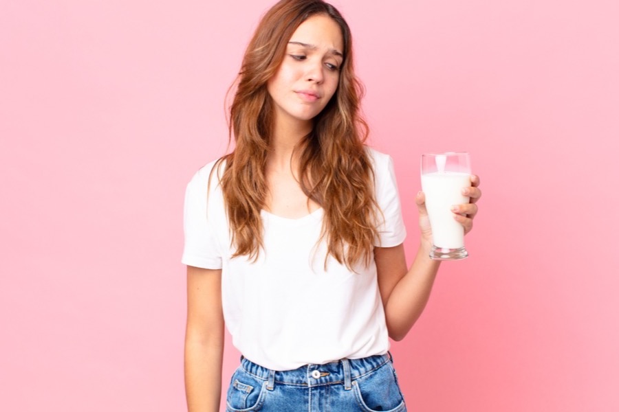 Woman evaluating a glass of milk, representing the debate over dairy and skin