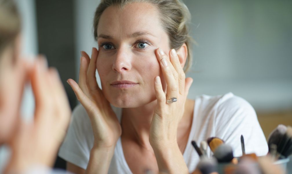 A woman examining her skin in a mirror