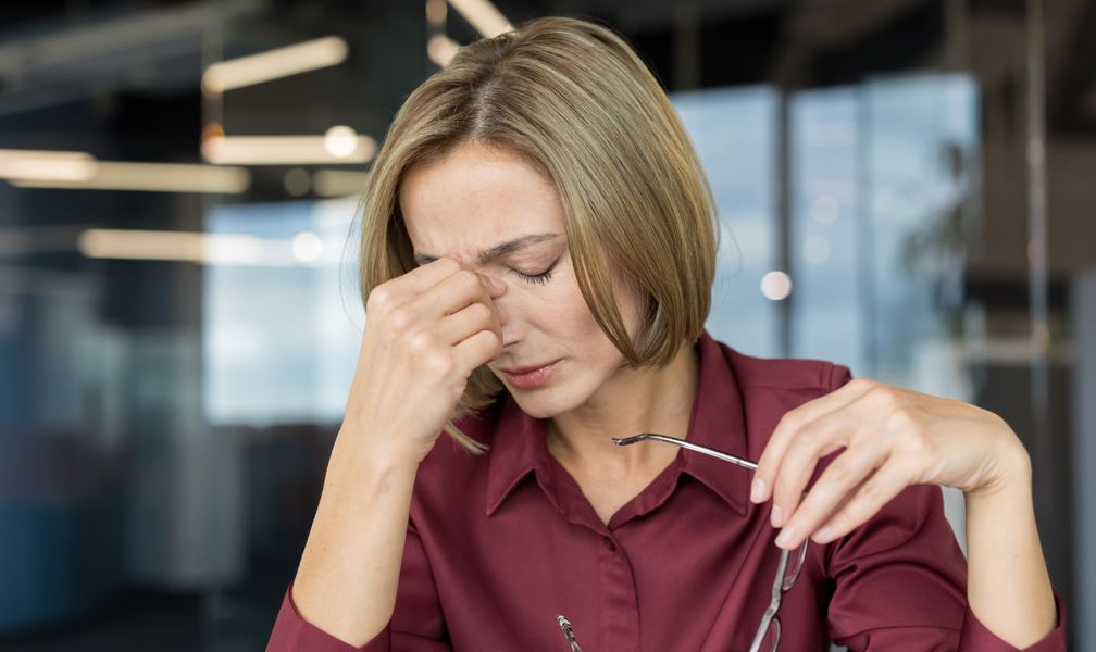 Stressed woman pinching the bridge of her nose at work